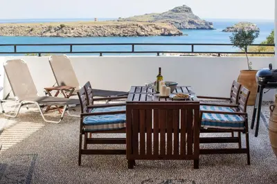 a table and chairs on a balcony with a view of the ocean at Villa Thalassa 2 Cozy Greek Comfort Private Shaded Courtyard in Líndos