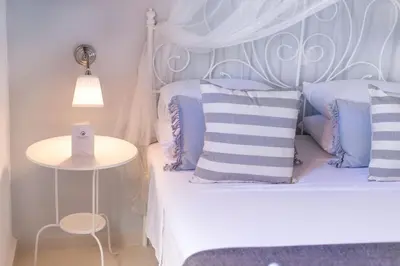 a bedroom with a white bed with blue pillows at Villa Thalassa 2 Cozy Greek Comfort Private Shaded Courtyard in Líndos