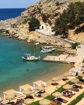 a beach with umbrellas and a boat in the water at Lindos Villa Aqua Euphoria ex Natura in Líndos