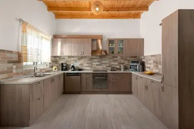 a large kitchen with wooden cabinets and a sink at Casa di Famiglia Rhodes in Koskinou