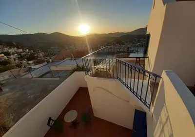 a balcony of a building with the sunset in the background at Symi Breeze villa in Symi