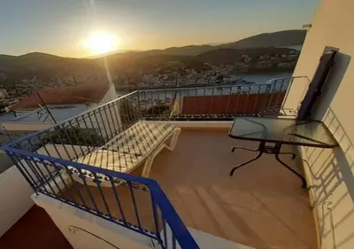 a balcony with a view of the sunset on a building at Symi Breeze villa in Symi