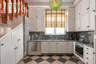 a kitchen with white cabinets and a sink and a chandelier at Casa Loma in Triánta