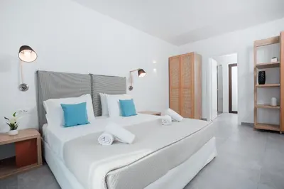a bedroom with a large white bed with blue pillows at Terra Pietra Luxury Villas & Suites in Lardos
