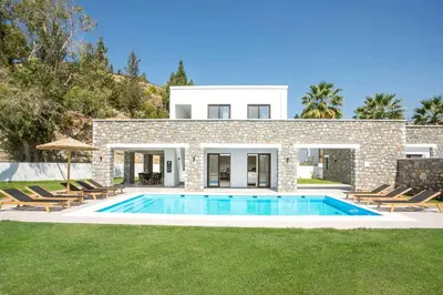 a villa with a swimming pool in front of a house at Terra Pietra Luxury Villas & Suites in Lardos