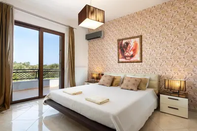 a bedroom with a large bed and a balcony at Villa Vergio in Afantou