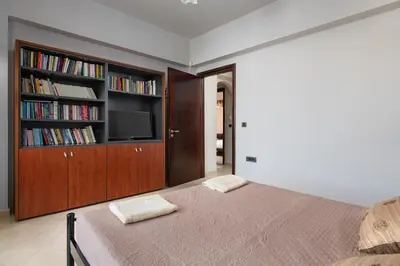 a bedroom with a bed and a tv and bookshelves at Villa Vergio in Afantou