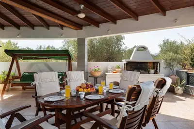 a patio with a table and chairs and a fireplace at Villa Vergio in Afantou