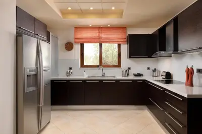 a kitchen with black cabinets and a stainless steel refrigerator at Villa Vergio in Afantou