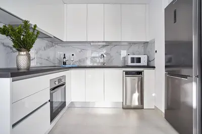 a white kitchen with a microwave and a refrigerator at Sia Mare Seaside Apartments in Faliraki