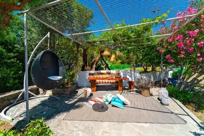 a patio with a table and a grill and flowers at Tselios Apartments & Studios in Kiotari