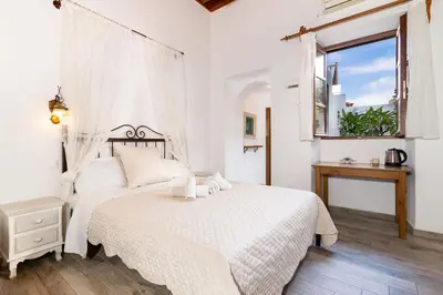 a white bedroom with a bed and a window at villa Zinovia in Líndos