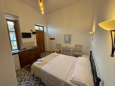 a bedroom with a bed and a desk and a television at villa Zinovia in Líndos