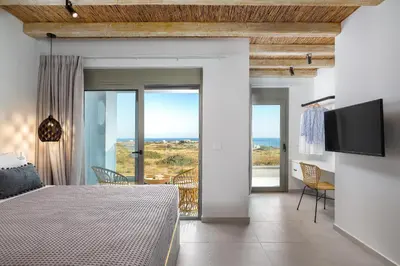 a bedroom with a bed and a view of the ocean at Anemos Villas in Lachania