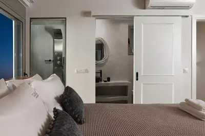 a bedroom with a bed with pillows and a bathroom at Anemos Villas in Lachania