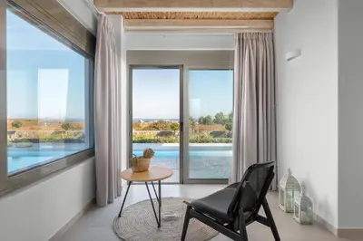 a room with a table and a chair in front of a window at Anemos Villas in Lachania