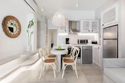 a white kitchen with a white table and chairs at Thalassa Luxury Studios Lindos in Líndos