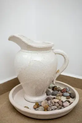 a white vase sitting on a plate with rocks at Casa Plumeria of Old Town Rhodes in Rhodes Town