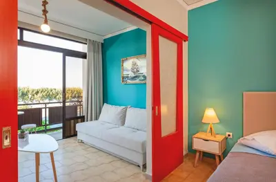 a room with a couch and a bed and a window at CHAMBRE ORANGE in Ialyssos