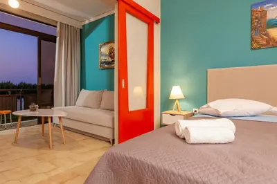 a bedroom with a bed and a couch and a table at CHAMBRE ORANGE in Ialyssos