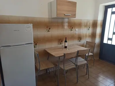a kitchen with a table and a bottle of wine at CHAMBRE ORANGE in Ialyssos