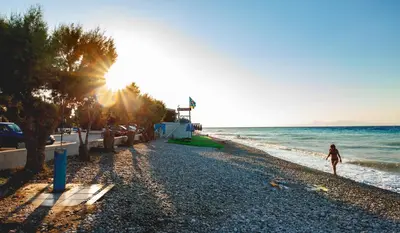 a woman walking on the beach at sunset at CHAMBRE ORANGE in Ialyssos