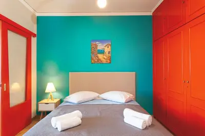 a bedroom with a bed with a blue wall at CHAMBRE ORANGE in Ialyssos