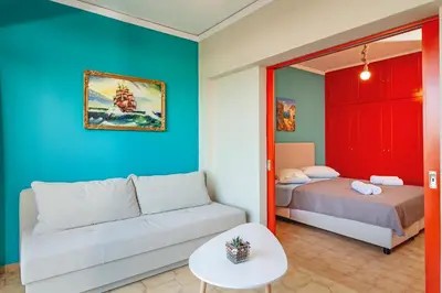 a living room with a couch and a bed at CHAMBRE ORANGE in Ialyssos