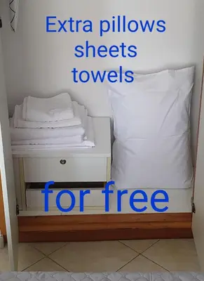 a bed with a white pillow and a sign that says extra pillows sheets towels at BLUE EYES APARTMENTS in Ixia