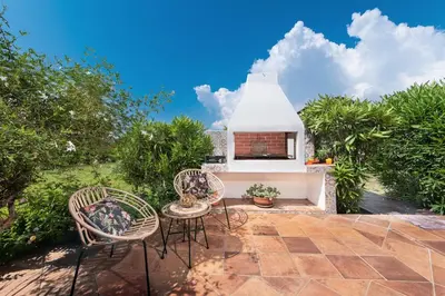 a patio with three chairs and a white house at Aelia Sea View Bungalow in Gennadi