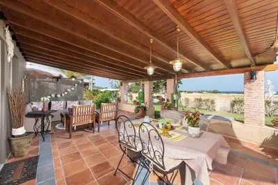 an outdoor patio with tables and chairs and a wooden pergola at Aelia Sea View Bungalow in Gennadi