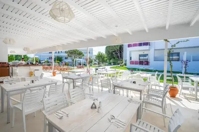 a restaurant with white tables and white chairs at Stamos All Inclusive in Faliraki