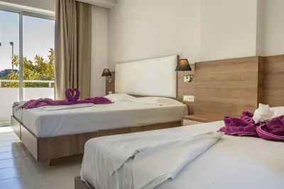 a hotel room with two beds with purple towels on them at Stamos All Inclusive in Faliraki