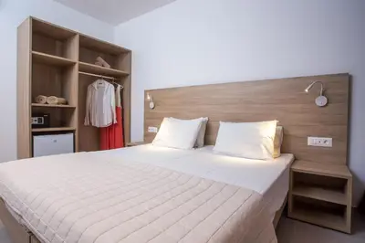 a bedroom with a large white bed with a wooden headboard at Stamos All Inclusive in Faliraki