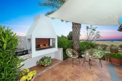 a backyard patio with a fireplace and chairs at Ilaira Sea View Bungalow in Gennadi