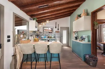 a kitchen with a blue island with stools at Ilaira Sea View Bungalow in Gennadi