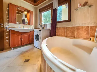 a bathroom with a tub and a sink and a washing machine at Colonial View Apartment in Faliraki