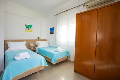 a bedroom with two beds and a wooden cabinet at Seascape Village - Spacious 3-Bed Apartment with Private Garden and Parking in Kalithies