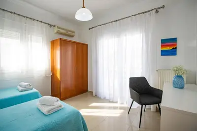 a bedroom with two beds and a chair and a desk at Seascape Village - Spacious 3-Bed Apartment with Private Garden and Parking in Kalithies