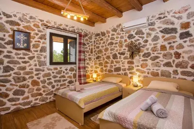 a bedroom with two beds and a stone wall at Villa in the Woods in Kolimbia