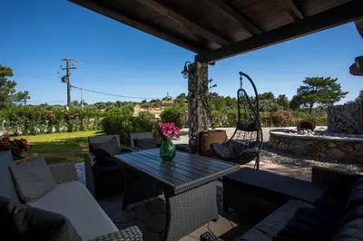 a patio with a table and chairs and a swing at Villa in the Woods in Kolimbia