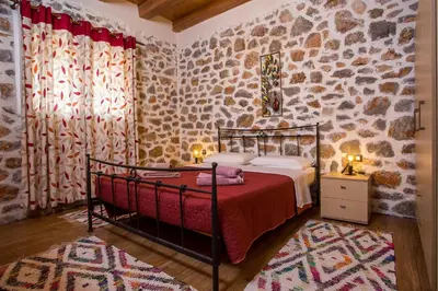 a bedroom with a bed and a stone wall at Villa in the Woods in Kolimbia