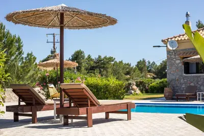 two chairs and an umbrella next to a pool at Villa in the Woods in Kolimbia