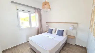 a bedroom with a white bed and a window at Villa Stamos with Seaview and Private Pool - Partner of Prasonisi Villas in Plimmiri