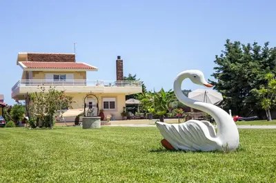 a statue of a swan in the grass in front of a house at Laylande House in Theologos