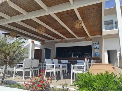 a patio with a bar with white chairs and tables at Stegna Premium in Archangelos
