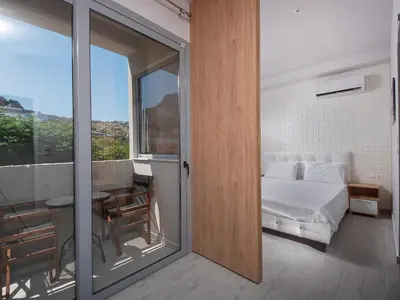 a bedroom with a bed and a balcony with a table at Stegna Premium in Archangelos