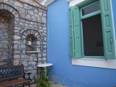 a window with a bench next to a stone wall at Andreas Apartments in Symi