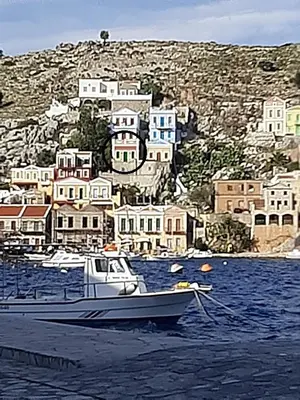 a boat sitting in the water in front of a town at Andreas Apartments in Symi