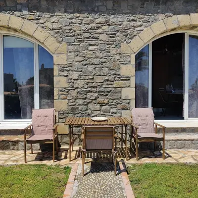 a table and chairs in front of a stone wall at Kiotari Stone House in Gennadi